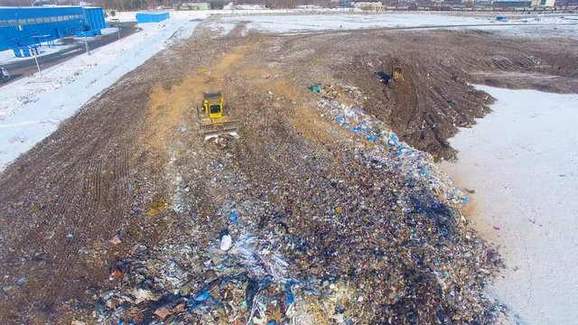 The bulldozer working at the landfill. Aerial. 4K.