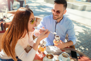 Dating in the cafe. Loving couple drinking coffee and eating the fruit desserts. Dating, love, relationships