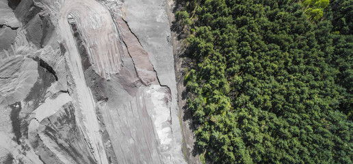 Border between industial site and gree forest. Aerial view of open pit sand.