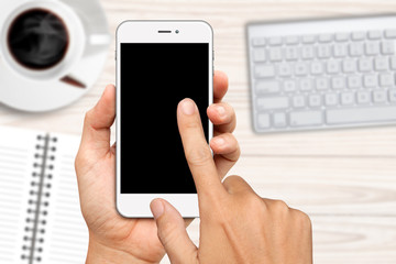 hand holding and touch on white smartphone with blank screen over work desk