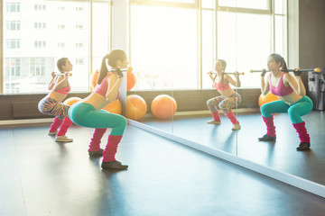 Squats with a barbell. Training in a sports club. Sunny morning sports mood