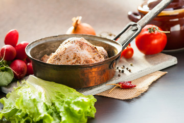 Marinated chicken meat in a pan, ceramic pot and vegetables 