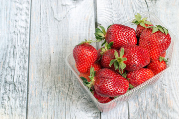   Strawberry.  Red ripe strawberry in a transparent plastic container on a wooden background.