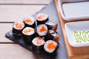 Sushi rolls with salmon and dishes with soy sauce and wasabi