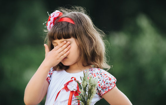 Little girl covers her face with her hand.