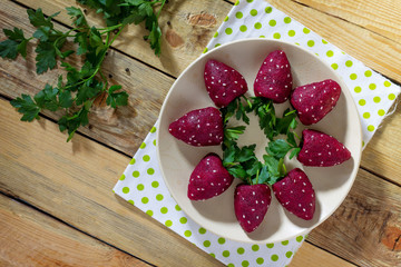Vegan snack on the festive table. Strawberries from boiled beets with a herring filling.