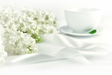 White lilac with ribbon and cup of tea at the morning