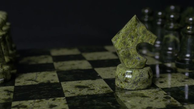 Ghess white horse defeats black pawn. Selective focus. Chess, Horse and pawn. Details of chess piece on black background.