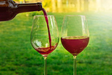 Red wine poured into glass at picnic, with copyspace