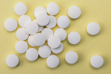 Many medicines white pills capsules on yellow bacground
