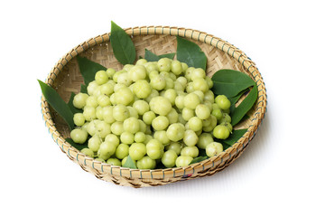 top view fresh Phyllanthus acidus or  star gooseberry with green leaves on bamboo basket background