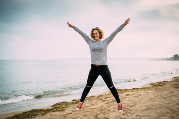 The girl jumps up and has fun near the sea