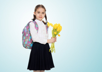 A schoolgirl with a bouquet of flowers and a backpack on her sho