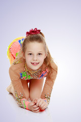 Beautiful girl gymnast sitting on the floor.