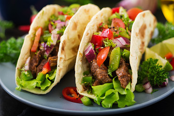 Mexican tacos with beef in tomato sauce and salsa