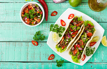 Mexican tacos with beef in tomato sauce and salsa
