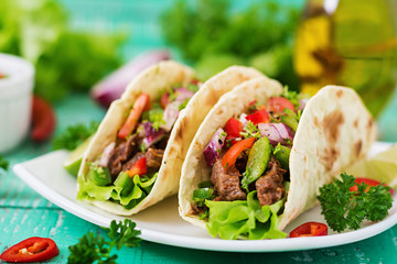 Mexican tacos with beef in tomato sauce and salsa