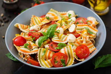 Pasta colored farfalle salad with tomatoes, mozzarella and basil.
