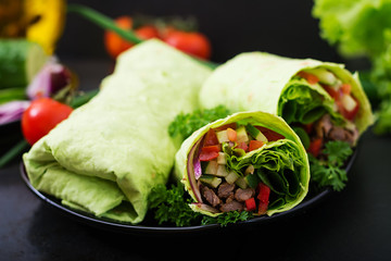 Shawarma from juicy beef, lettuce, tomatoes, cucumbers, paprika and onion in pita bread with...