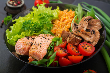 Healthy salad with salmon, tomatoes, mushrooms, lettuce and lentil on dark background