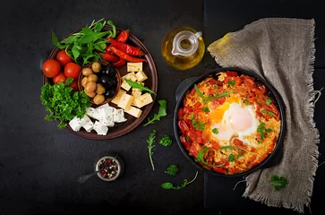 Foto op Canvas Breakfast. Fried eggs with vegetables - shakshuka in a frying pan on a black background in the Turkish style. Flat lay. Top view © timolina