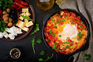 Breakfast. Fried eggs with vegetables - shakshuka in a frying pan on a black background in the Turkish style. Flat lay. Top view