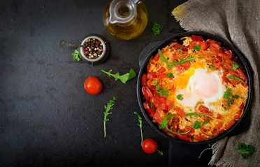 Foto auf Acrylglas Breakfast. Fried eggs with vegetables - shakshuka in a frying pan on a black background in the Turkish style. Flat lay. Top view © timolina