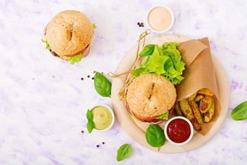 Big sandwich - hamburger with juicy beef burger, cheese, tomato, and red onion on light background and French fries. Top view. Flat lay