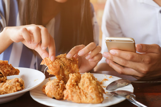 Close Up Man Hand Holding Smartphone Talking With Woman Who Try To Eat Fired Chicken For Lunch Break.