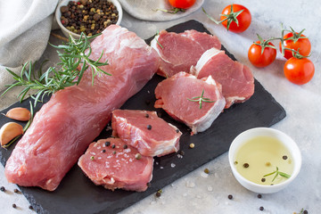 Fresh meat raw fillet with cherry tomatoes, onions, spices and rosemary on a cutting board.