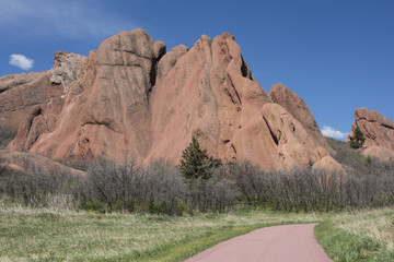 Paved walking path through park with large dramatic red sandstone formations