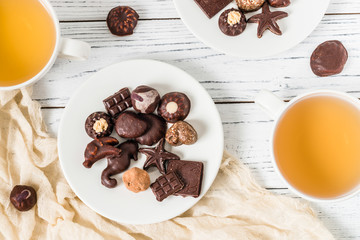 Raw handmade chocolate candies, two cups of tea on white wooden background. Healthy breakfast with vegan sweets. Top view