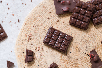 Bars of raw homemade chocolate on wooden cut. Vegetarian concept of healthy food. Top view
