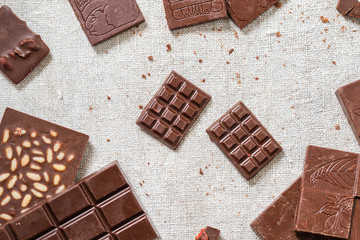 Variety of bars of raw homemade chocolate on cloth background. Vegetarian concept of healthy food. Top view