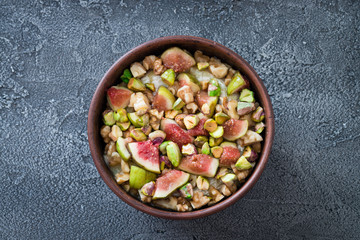 Raw chopped figs, walnuts, pistachios and honey with soft cheese in a bowl. Snack concept. Top view on dark background