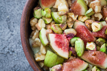 Raw chopped figs, walnuts, pistachios and honey with soft cheese in a bowl. Snack concept. Top view, close up