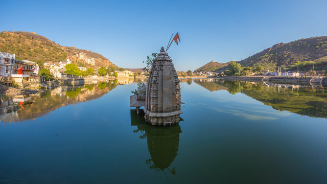 Bundi cityscape, travel destination in Rajasthan, India. The majestic fort perched on mountain slope overlooking the blue city.  Wide angle view frome the water pond.