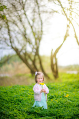 Obraz premium little girl in the park on a sunset, collects a bouquet of dandelions
