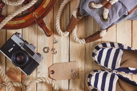 Striped slippers, camera, bag and maritime decorations, top view