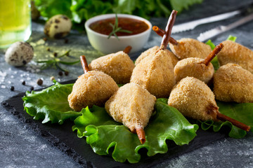 Spicy fried quail legs, chicken in batter with breadcrumbs on the kitchen table. Fast food.