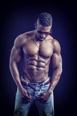 Fototapeta na wymiar African American bodybuilder man, naked muscular torso, wearing jeans and sunglasses, on black background