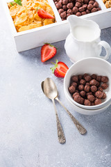 Milk jug and variety of cold quick breakfast cereals with berries in white wooden box, healthy eating concept, selective focus, copy space.