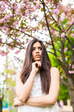 Portrait of beautiful young woman enjoying sunny day in park during cherry blossom season on a nice spring day