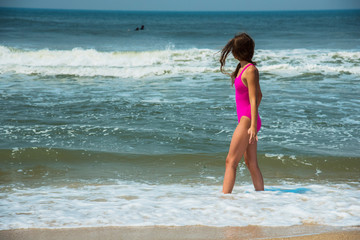Fototapeta na wymiar Sport girl-teenager in a pink bathing suit on background of ocean. Atlantic ocean. Porto, Portugal
