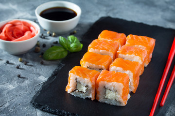 Roll Cheese salmon on a black slate board - salmon, soft cheese, nori, rice.