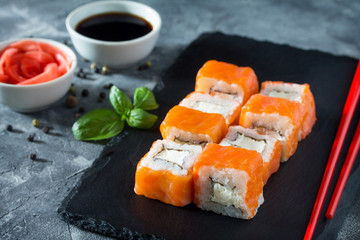Roll Cheese salmon on a black slate board - salmon, soft cheese, nori, rice.