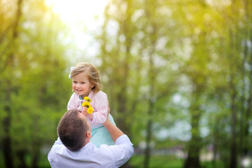 father throws the little daughter, in the park on a sunset