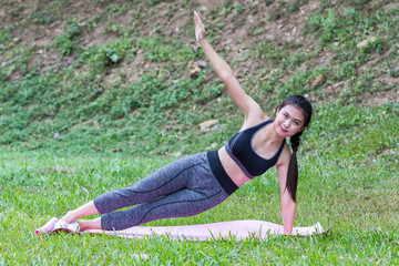 Fototapeta premium Pretty asian girl practicing the side plank yoga pose on yoga mat