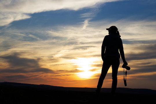 Silhouette Woman Photographing Landscape At Sunset. Female photographer holding a camera. Adventure concept at nature