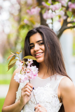 Joyful positive caucasian woman posing with flowering sakura tree.